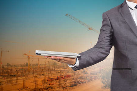 Businessman holding a tablet computer blurred of construction site backgroundの写真素材