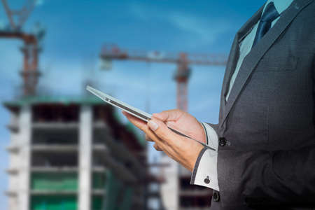 Businessman holding a tablet computer blurred of construction site background