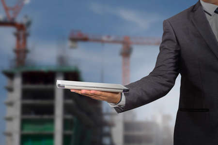 Businessman holding a tablet computer blurred of construction site backgroundの写真素材