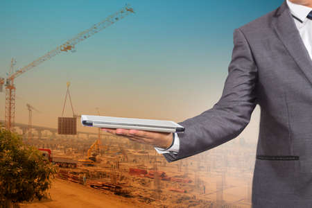Businessman holding a tablet computer blurred of construction site backgroundの写真素材