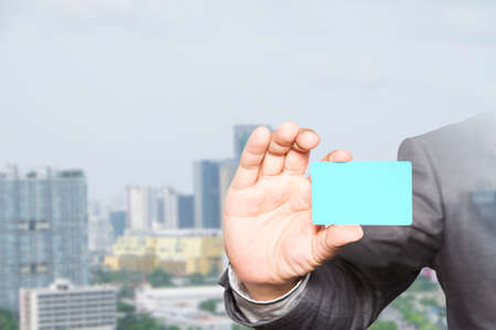 businessman holding visit card in hand and standing with building, business idea conceptの写真素材