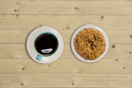 Overhead view of doughnut and a cup of strong black filter or espresso coffee on a rustic wood tableの写真素材