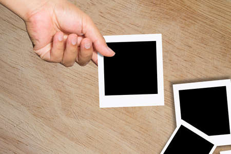 Blank instant photo in man's hand - place your own picture on it.の写真素材