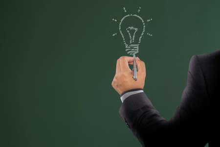Businessman drawing light bulb on board. Light bulb idea for inspiration creativeの写真素材