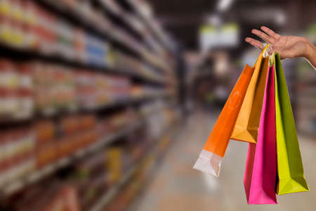 Happy shopping. woman hand holding multicolored shopping bags over mall backgroundの写真素材