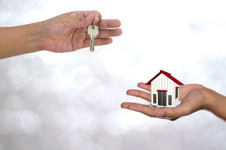 Real estate agent with house model and keys on green backgroundsの写真素材