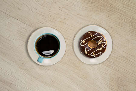 Overhead view of doughnut and a cup of strong black filter or espresso coffee on a rustic wood tableの写真素材