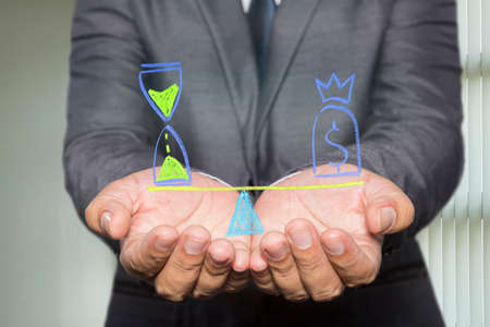 Businessman holding diagram with Scales in equal balance holding a clock left on the and money on the right.の写真素材
