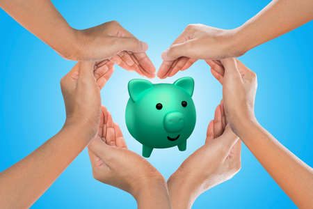 piggy bank in heart formed by female handsの写真素材