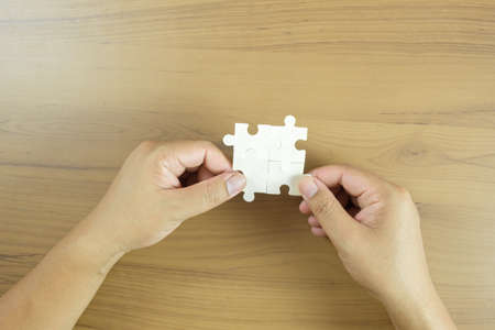Hand holding piece of blank jigsaw puzzleの写真素材