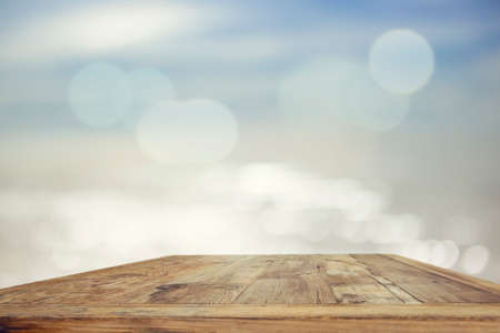 Wood table top on blurred blue sea background - used for display or montage your products. Vintage effect filter style picturesの写真素材