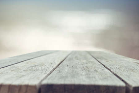 Wood table top on blurred blue sea background - used for display or montage your products. Vintage effect filter style picturesの写真素材