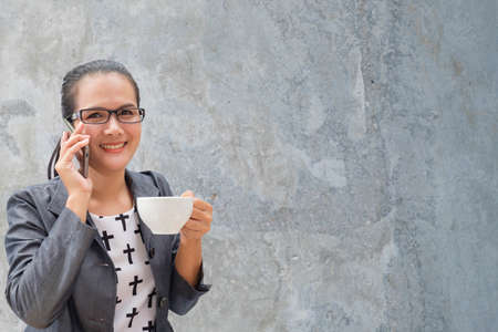 Young businesswoman using smartphone and drinking coffeeのeditorial素材