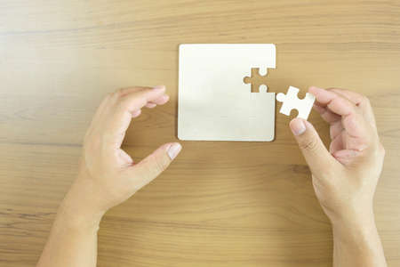 Hand holding piece of blank jigsaw puzzleの写真素材