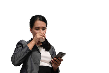 Young asian woman lawyer looking at mobile smartphone and drinking coffee from disposable paper cup.のeditorial素材
