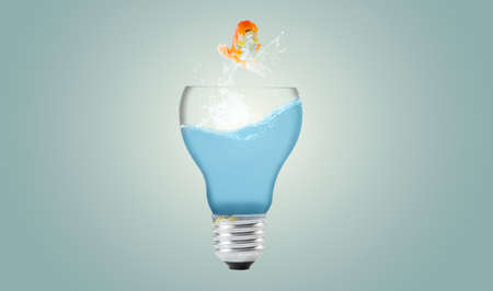 Goldfish jumping out light bulbの写真素材