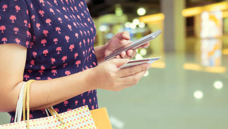 Concept of payment by plastic card at big shopping centre. Close-up of asian woman's hand holding credit card and bags with purchases - Vintage Filterの写真素材