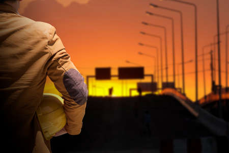 worker or engineer holding in hands helmet for workers security on background of new highrise apartment buildings and construction cranes on background.のeditorial素材