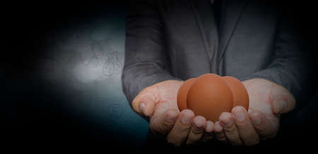 Young businessman holding one egg in handのeditorial素材