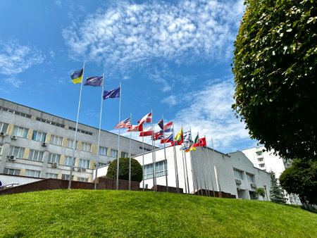 Many flags of different countries against the background of government buildings and blue sky. flagpoles.の写真素材