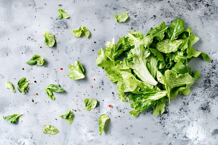 Fresh lettuce leaves sprinkled with salt and pepper resting on a gray textured background, creating...