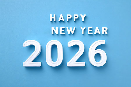 White dimensional text spelling happy new year 2026 appears on a textured blue surface, symbolizing...