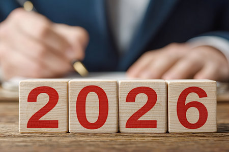 Business person writing notes on a document with wooden blocks showing the year 2026, representing...