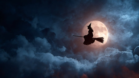 Witch silhouette on a broomstick crossing a glowing full moon amid cloudy night sky, evoking halloween magic, mystery and eerie fantasy atmosphere perfect for spooky themesの写真素材