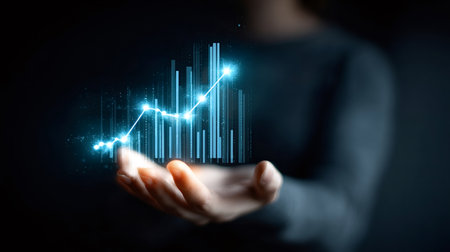 Individual's hand presenting a glowing blue digital graph and bar chart, visualizing financial success, data analytics, and technological advancement in businessの写真素材