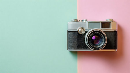 Retro analog film camera lying flat on a split pastel background with soft pink and green hues, representing photography, memories, and minimalist designの写真素材