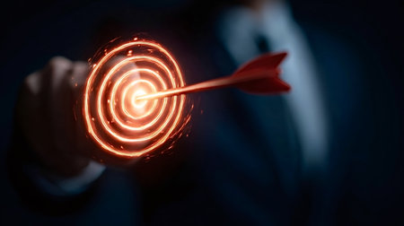 Businessperson's hand reaching and an arrow striking a glowing digital target, representing focus, strategy, and successful goal achievement in a dark, professional settingの写真素材