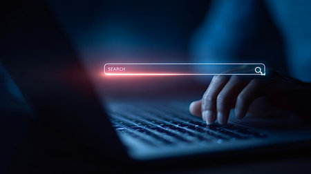 Person's hand typing on a laptop keyboard with a glowing search bar overlay, representing online information access, digital networking, and global data connectionsの写真素材