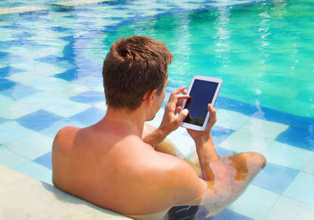man poolside holding tablet computerの写真素材