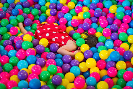 Little Girls playing lying in colorful balls park playgroundの写真素材
