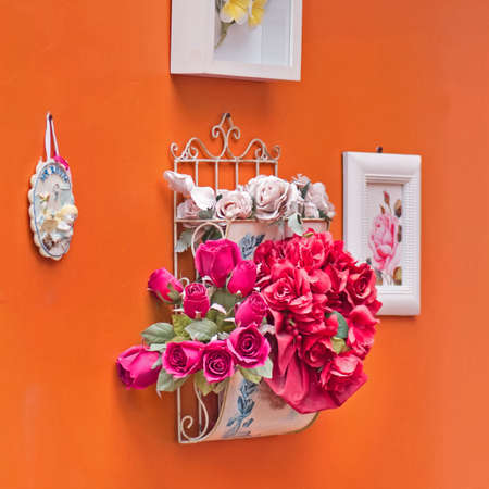 Artificial flowers on Orange wall , Vintage style and a frame attached to the side.の写真素材