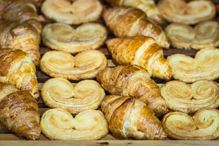 Box of breakfast pastries. Two wooden trays, flaky croissants, and apple danishes.の写真素材