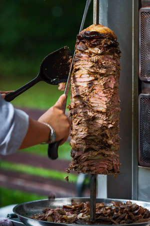 An arm moving to cut the kebab meatの写真素材