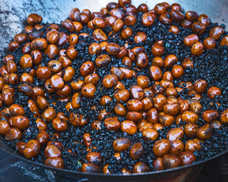 The making of Fried chestnuts on the street. Street food. Roasted chestnuts served in a special perforated chestnut pan.の写真素材