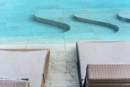 Swimming pool with beach chairs in resort.の写真素材