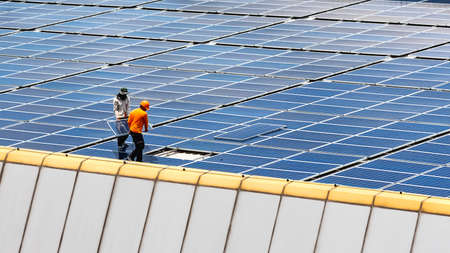 A Technician installing a solar panels on the factory roof.