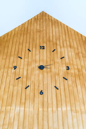 Analog clock with hands and numbers in black on brown wood wall.