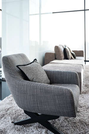 Black and white armchairs in the living room on the 29th-floor luxury apartment. There is a bare glass wall overlooking the city.の写真素材