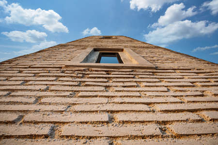window on brown brick wall and sky and cloudsの写真素材