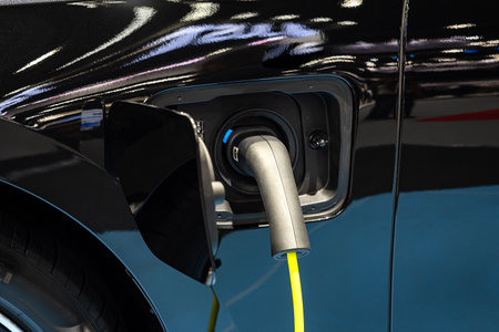 Power cable pump plug in charging power to electric vehicle EV car with modern technology UI control information display, car fueling station connected power cable alternative sustainable eco energyの写真素材