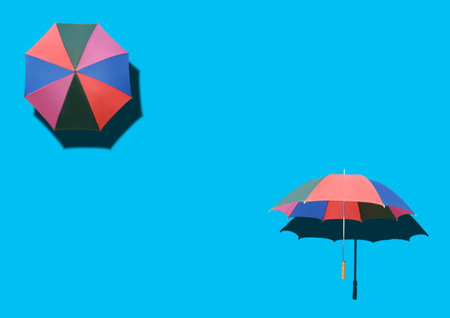 Top view, Two rainbow umbrella isolated on cyan background for stock photo or design, invesment, business, summer conceptの写真素材