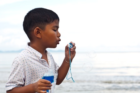young asian boy blowing bubbleの写真素材