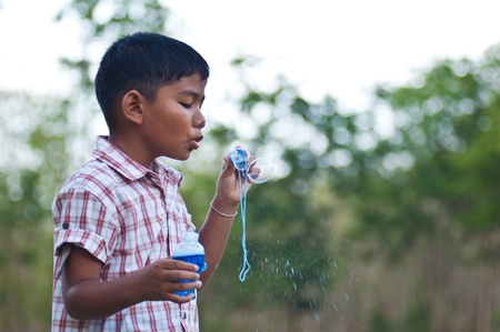 young asian boy blowing bubbleの写真素材