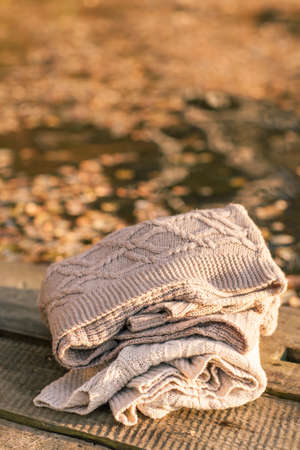 Pile of knitted winter clothes on wooden background, sweaters, knitwear
