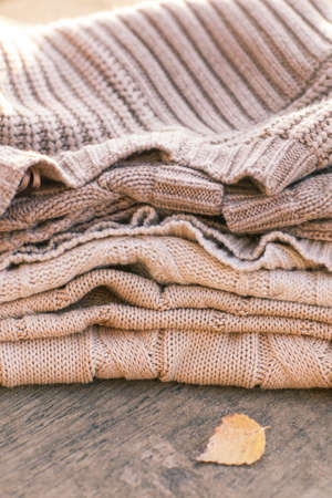 Pile of knitted winter clothes on wooden background, sweaters, knitwear