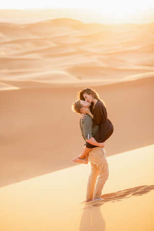 Young couple enjoying the sunset in dunes. Romantic traveler walking on the Sahara desert. Adventure travel lifestyle concept.の写真素材